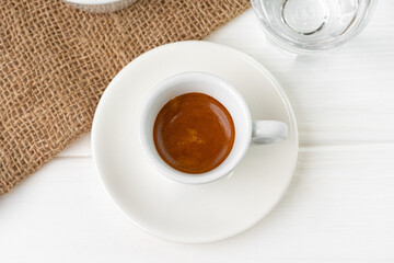 Cup of espresso with glass of water on white table