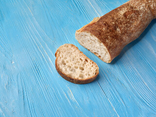 French baguette with sliced bread on blue wooden table.