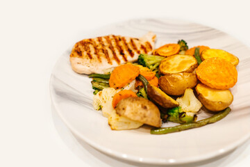 Grilled vegetables and chicken fillet on plate.