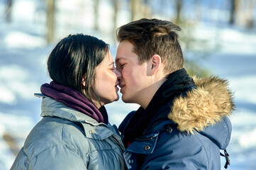 Fototapeta premium Young couple kissing outdoors in a winter park close up