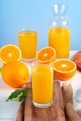 Glass of orange juice and cut oranges on table