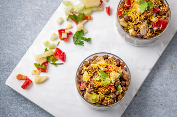 black gram or kala chana chaat with boiled potato, onion, tomato with a dash of lemon juice served on  glass bowls