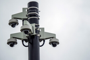 Four spherical CCTV cameras fixed on a black metal pole. Security and safety concept.