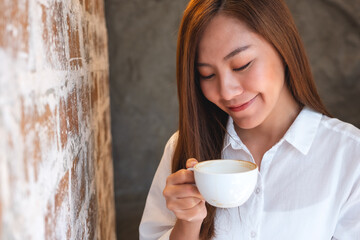 A beautiful young asian woman smelling and drinking coffee in cafe