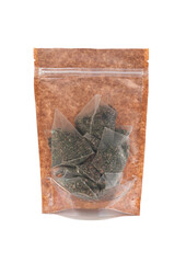Green tea bags in a brown paper bag. Doy-pack with a plastic window for bulk products. Close-up. White background. Isolated.