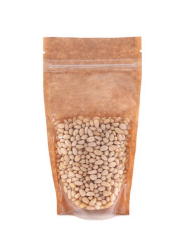 Peeled pine nuts in a brown paper bag. Doy-pack with a plastic window for bulk products. Close-up. White background. Isolated.