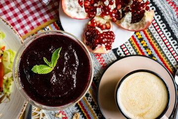 a cup of coffee on a table in a coffe shop in a beige mug . coffee with pomegranat, tea, restaurant, enjoy the taste dessert, cake, pastry, drink coffee, coffee to go,