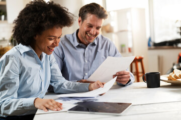  Young couple sitting in the kitchen preparing bills to pay. Stressed woman and man having financial problems.