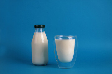 a bottle and a glass of kephir isolated on blue background. Fermented food concept