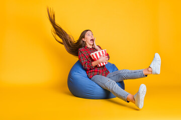 Portrait of beautiful trendy funky amazed girl sitting in bag eating corn having fun wind blowing...