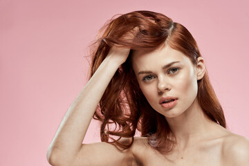 Cute red-haired woman naked shoulders clean skin care pink background