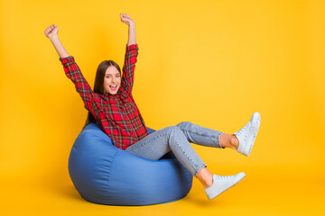 Portrait of attractive cheerful lucky girl sitting in bag chair having fun isolated over bright...