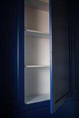 open cabinet without handles in the wall in blue color