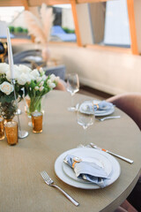 a wooden table set with white plates and blue napkins. Fresh flowers on the table on the background of the dome from the windows