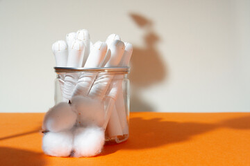 Fototapeta na wymiar Glass jar with hygienic tampons and cotton flower
