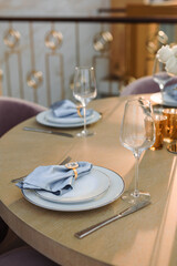 a wooden table set with white plates and blue napkins. Fresh flowers on the table on the background of the dome from the windows
