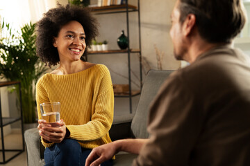 Young couple sitting and talking at home. Woman and man flirting and laughing..