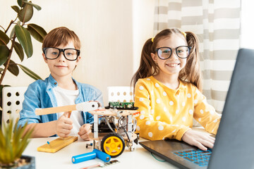 Education science, technology, children and people concept - happy kids or students with tablet pc computer programming electric toys at robotics school lesson