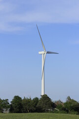 Electric Windmill with blue sky east  of Wilson Kansas USA out in the country with tree's.