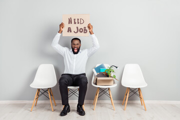 Full length body size photo of angry man sitting waiting for interviews shouting need job money showing cardboard