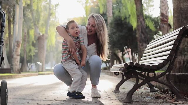 Happy mom play with her son during they walking outdoors. Kid with physical diability. Video of enjoy happy love family outdoors. Happy moments. Disability care concept