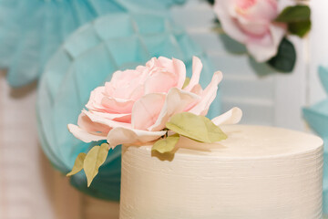 Top of wedding or birthday cake with tender rose flower on festive candy bar background.
