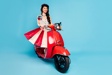 Fototapeta na wymiar Portrait of attractive cheerful girl riding moped carrying home bringing new things bargain isolated on bright blue color background