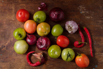 Seasonal harvest, autumn vegetables, hot pepper, garlic, unripe green tomatoes on wooden table. Farmer organic no animal products. Top view