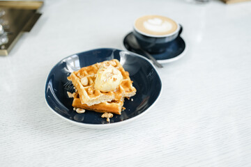 breakfast of Viennese waffles with mousse and cappuccino on the table at the hotel