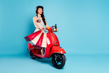 Portrait of attractive cheerful girl riding moped delivering bringing new things isolated on bright blue color background