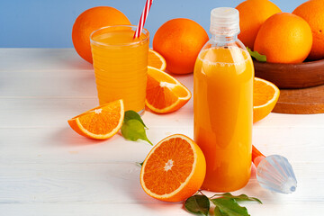 Bottle of orange juice and fresh oranges on table
