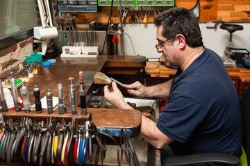goldsmith sands a silver ring on the workbench.