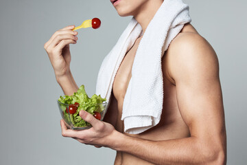 athletic man with muscular body plate with salad towel on shoulders cropped view eating