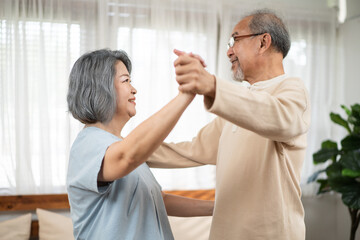 Asian senior couple dancing together in free time at the living room.