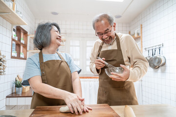 Asian senior couple helping each other for homemade bakery cooking.