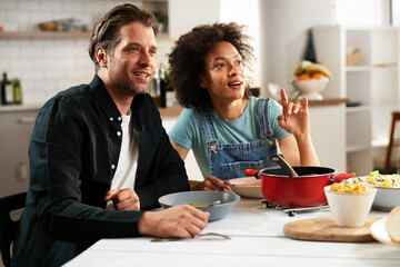 Boyfriend and girlfriend eating lunch together at home. Husband and wife enjoying in delicious food.