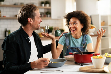 Boyfriend and girlfriend eating lunch together at home. Husband and wife enjoying in delicious food.