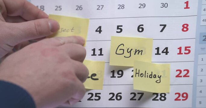 The hand sticks a reminder on the calendar about the meeting. meeting. an important event. reminder card. Real love. February 14. Hollyday. Friend's meeting. Important day. Gum, sport
