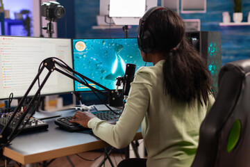 African space shooter e-sport player playing live game with friends speaking into microphone. Streaming viral video games for fun using headphones and keyboard for online championship. © DC Studio