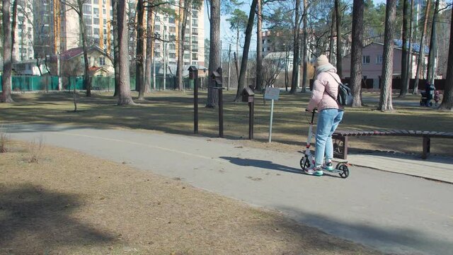 Woman riding scooter in the park tracking camera movement