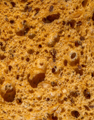 Slice of Brown Rye Fresh Bread with grains as background, top view. Macro Close-up