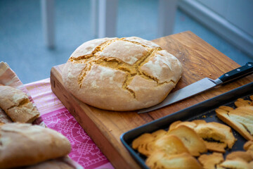 pan casero tradicional, hogaza al horno sobre tabla de madera con cuchillo. traditional homemade bread, baked loaf on wooden board with knife.