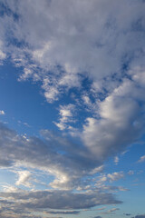Clouds in the blue sky. Vertical layout of the image. Contrasting clouds.