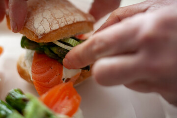 Manos elaborando  tapas de salmón, queso fresco y espárragos. Hands making tapas with salmon, fresh cheese and asparagus.