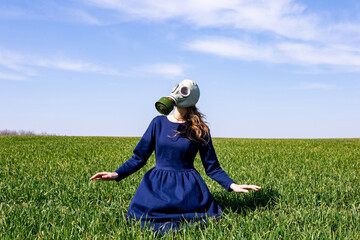 A young girl in a gas mask stands in a green field. Pandemic. Coronavirus.