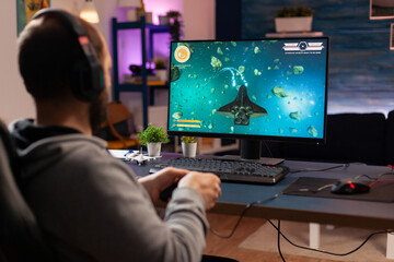 Gamer player with headphones performing videogame with modern graphics for space shooter championship. Online streaming cyber performing during gaming tournament using technology network wireless © DC Studio
