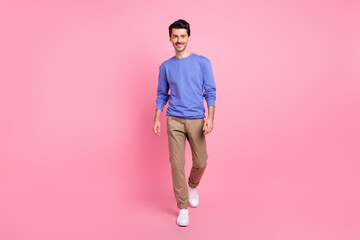 Fototapeta na wymiar Full length photo of charming positive young man walk step wear casual clothes isolated on pink color background