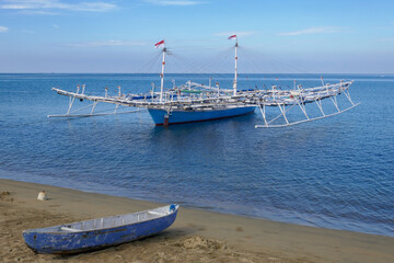 Outrigger boat used for night fishing and small canoe on beach in Polewali, West Sumatra, Indonesia