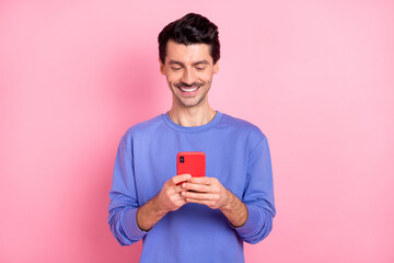 Photo of positive young man hold smartphone chat social media blogger isolated on pink color background