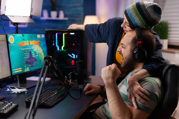 Players couple winning online videogames competition using professional equipment in home studio. Gamer playing video games with new graphics on powerful gaming computer with RGB